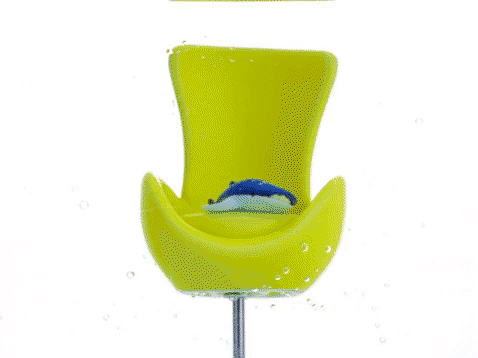 do akwarium w którym stoi mini krzesełko wlewa się niebieska i żółta farba tworząc piękny fajerwerk kolorów